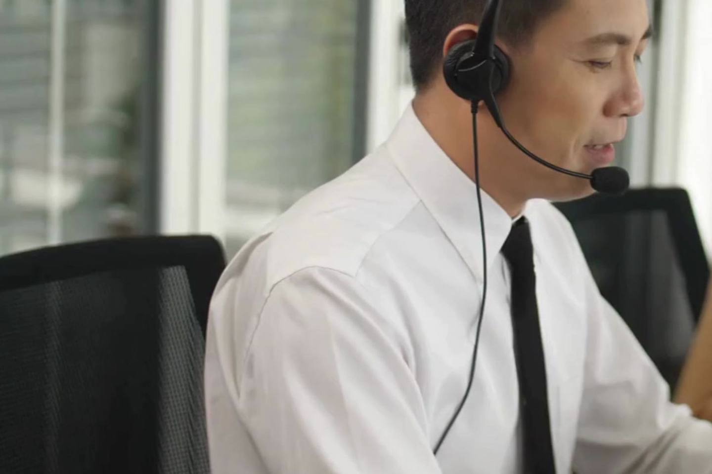 A support agent wearing a headset, taking a call at their desk